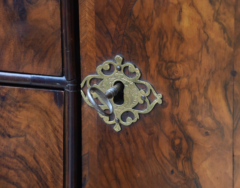 A late 17th-century William and Mary walnut cabinet on chest featuring double cupboard doors above drawers with brass mounts and bun feet. View IX