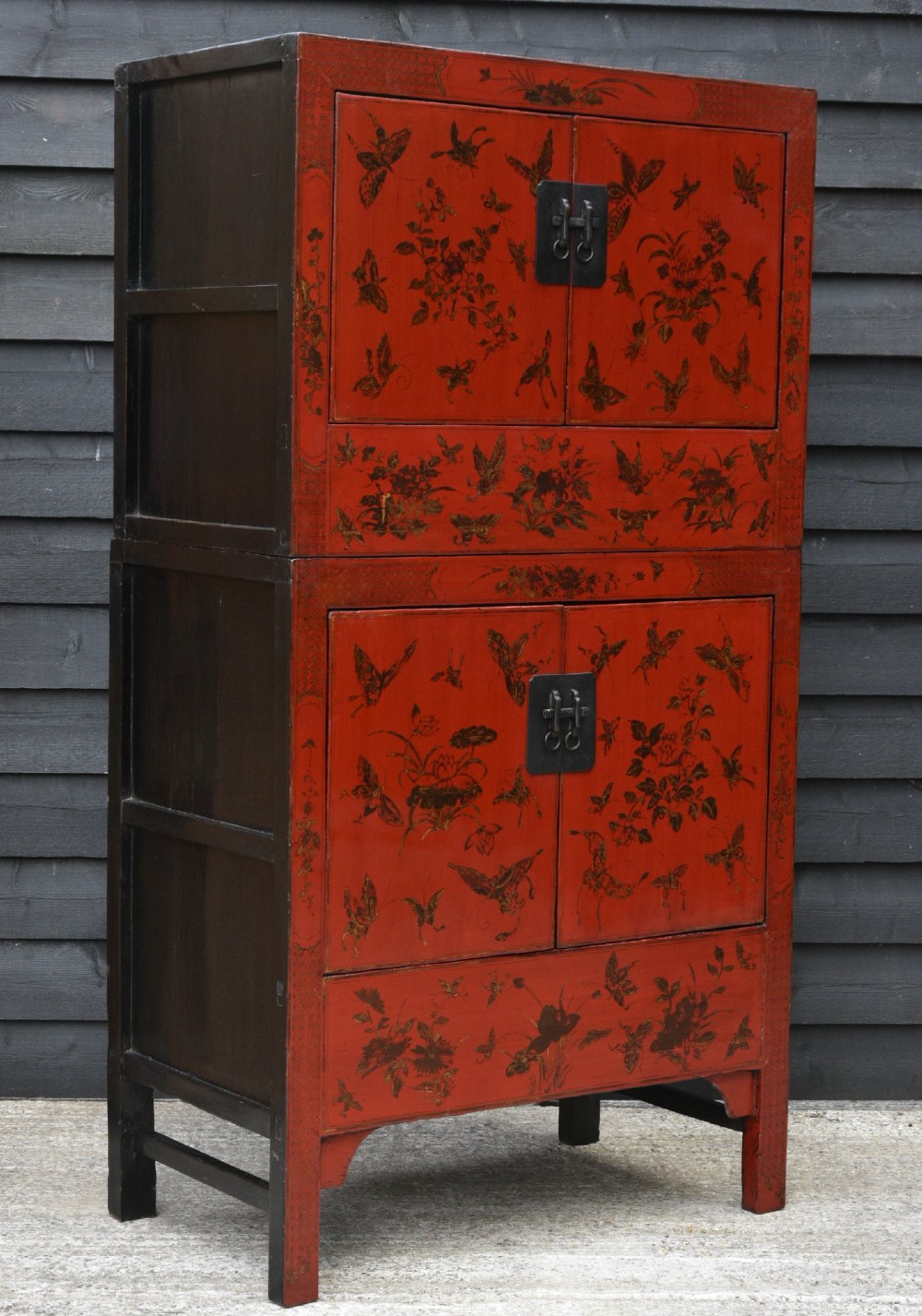 A tall two-tier red lacquered Chinese cabinet decorated with gold floral and butterfly paintings and dark metal door hardware. View VI