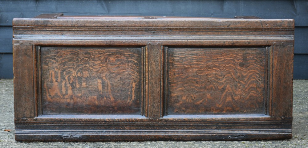 A 17th-century dark oak panelled coffer box with a hinged lid, twin front panels, and a central iron escutcheon. View V