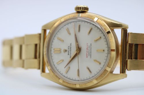 fig 1. A mid-century yellow gold Rolex Oyster Perpetual wristwatch with an engine-turned bezel, cream dial, dagger hour markers, and matching gold bracelet.