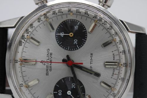 fig 3. A vintage 1969 Breitling Top Time wristwatch with a silver panda dial, two black sub-dials, a central red hand, and a black leather strap.