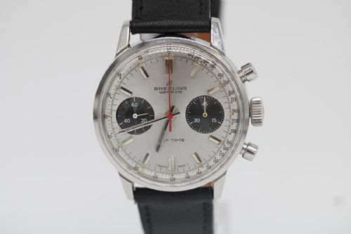 fig 4. A vintage 1969 Breitling Top Time wristwatch with a silver panda dial, two black sub-dials, a central red hand, and a black leather strap.