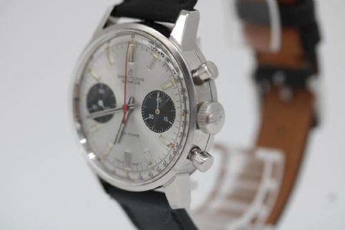 fig 6. A vintage 1969 Breitling Top Time wristwatch with a silver panda dial, two black sub-dials, a central red hand, and a black leather strap.