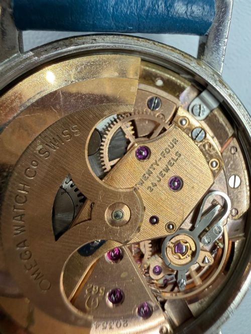 fig 3. A 1963 stainless steel Omega Seamaster automatic wrist watch featuring a silver dial with baton indices, date window at three oclock, and a blue leather strap.