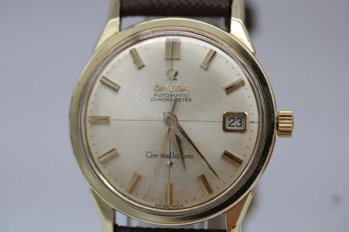 fig 6. A 1962 vintage Omega Constellation wristwatch featuring a gold pie-pan dial, date aperture, and brown leather strap.
