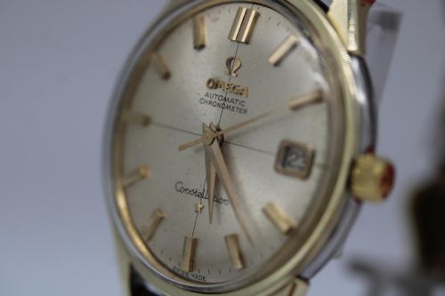 fig 7. A 1962 vintage Omega Constellation wristwatch featuring a gold pie-pan dial, date aperture, and brown leather strap.