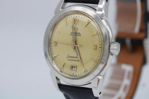 fig 4. A vintage 1952 Omega Seamaster Calendar wristwatch featuring a stainless steel case, textured gold-coloured dial with date display at six oclock, and a black leather strap.
