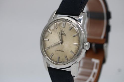 fig 3. A 1950s stainless steel Omega Seamaster wristwatch featuring a patinated cream dial with silver baton indices and a black leather strap.