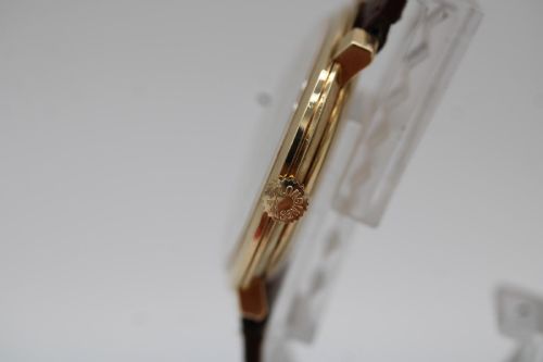 fig 5. A vintage circular 9ct gold wristwatch by Longines featuring a silver dial with gold baton hour markers and a brown leather strap.