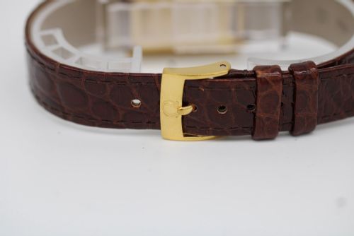fig 2. A 1960s Omega Geneve manual wind wristwatch featuring an 18ct yellow gold cushion-shaped case, a dark brown dial with gold Roman numerals at twelve and six, and a brown leather strap.