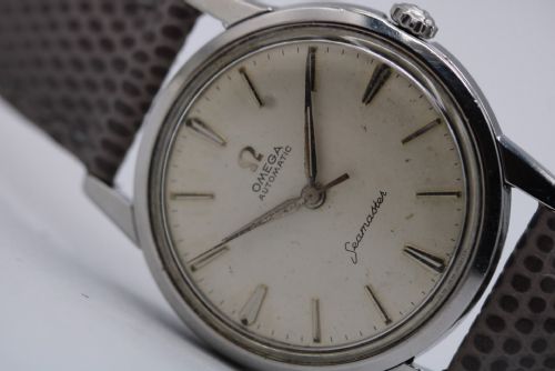 fig 2. A vintage 1960 Omega Seamaster automatic wristwatch with a stainless steel case, silver cream dial, and grey textured leather strap.