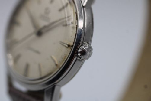 fig 4. A vintage 1960 Omega Seamaster automatic wristwatch with a stainless steel case, silver cream dial, and grey textured leather strap.