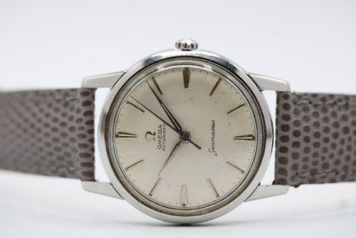 fig 5. A vintage 1960 Omega Seamaster automatic wristwatch with a stainless steel case, silver cream dial, and grey textured leather strap.