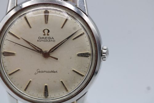 fig 6. A vintage 1960 Omega Seamaster automatic wristwatch with a stainless steel case, silver cream dial, and grey textured leather strap.