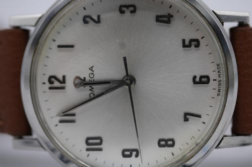 fig 2. A 1967 stainless steel Omega wristwatch featuring a white dial with black Arabic numerals and a tan brown leather strap.