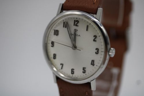 fig 4. A 1967 stainless steel Omega wristwatch featuring a white dial with black Arabic numerals and a tan brown leather strap.