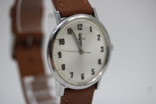 fig 5. A 1967 stainless steel Omega wristwatch featuring a white dial with black Arabic numerals and a tan brown leather strap.