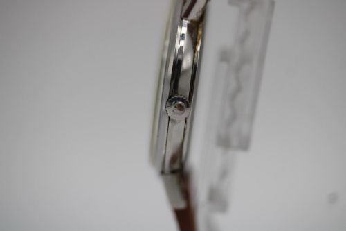 fig 6. A 1967 stainless steel Omega wristwatch featuring a white dial with black Arabic numerals and a tan brown leather strap.
