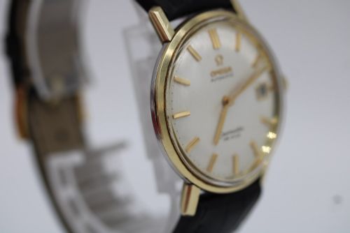 fig 9. A vintage gold-plated Omega Seamaster DeVille automatic wristwatch with a white textured dial, gold baton indices, date window, and black leather strap.