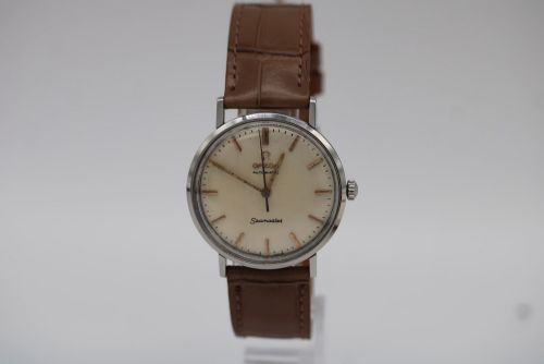 fig 1. A vintage 1961 Omega Seamaster wristwatch with a stainless steel case, silver dial, applied baton hour markers, and a tan leather strap.