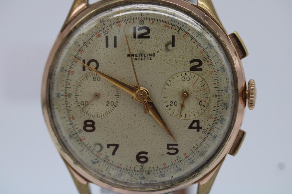 A 1950s Breitling Cadette chronograph wristwatch featuring a circular gold-plated case, twin sub-dials, Arabic numerals, and a blue textured leather strap. View III