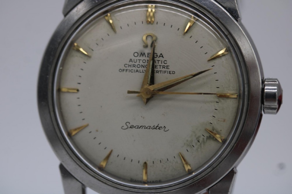 A vintage 1956 Omega Seamaster automatic wristwatch featuring a silver-coloured stainless steel case, off-white dial with gold-tone markers, and a navy blue leather strap. View IV
