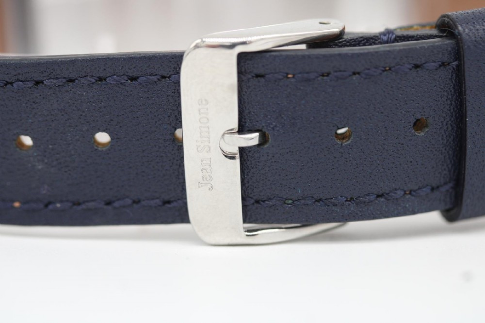 A vintage 1956 Omega Seamaster automatic wristwatch featuring a silver-coloured stainless steel case, off-white dial with gold-tone markers, and a navy blue leather strap. View V