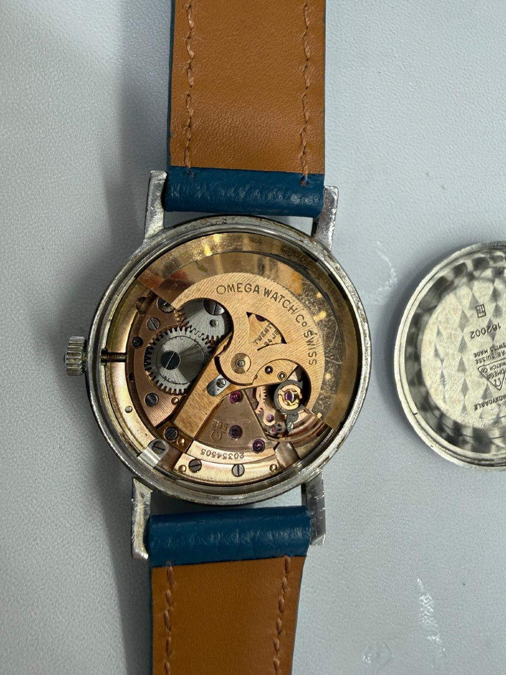 A 1963 stainless steel Omega Seamaster automatic wrist watch featuring a silver dial with baton indices, date window at three oclock, and a blue leather strap. View III