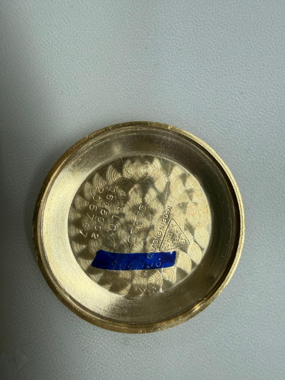 A 1962 Omega automatic wristwatch featuring a round 9ct gold case, silver dial with baton indices, and a blue textured leather strap. View IV