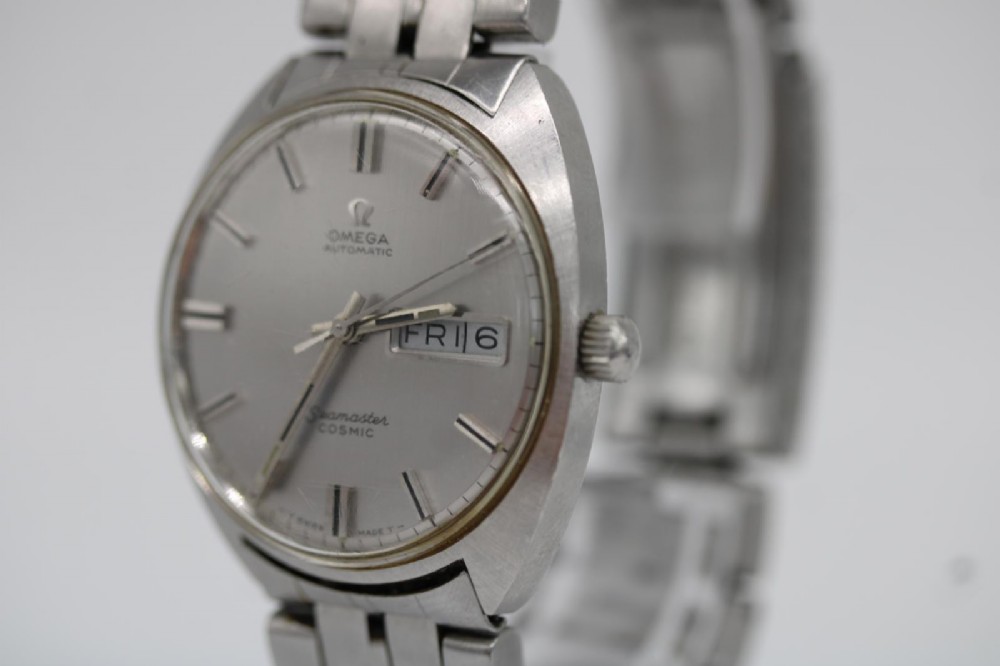 A vintage stainless steel Omega Seamaster Cosmic wristwatch featuring a silver dial with day-date window and metallic link bracelet. View IV