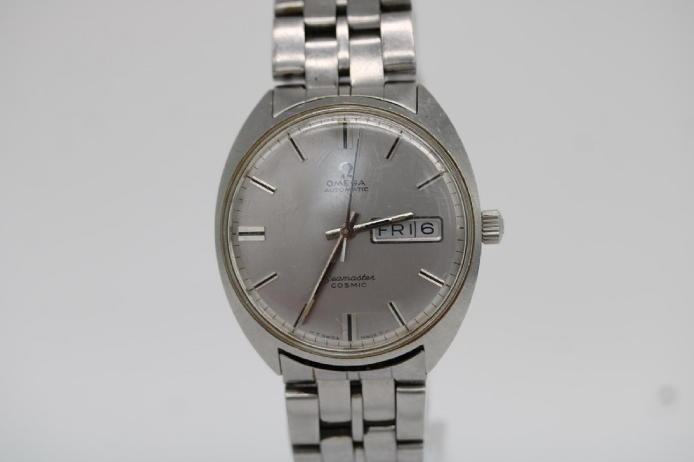 A vintage stainless steel Omega Seamaster Cosmic wristwatch featuring a silver dial with day-date window and metallic link bracelet.