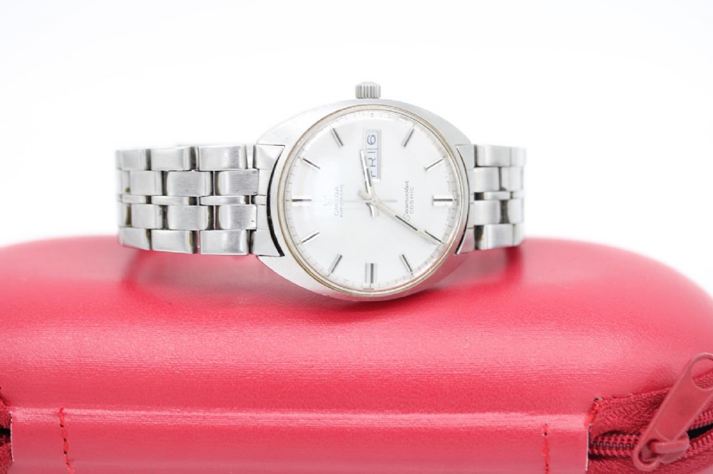 A vintage stainless steel Omega Seamaster Cosmic wristwatch featuring a silver dial with day-date window and metallic link bracelet. View VIII