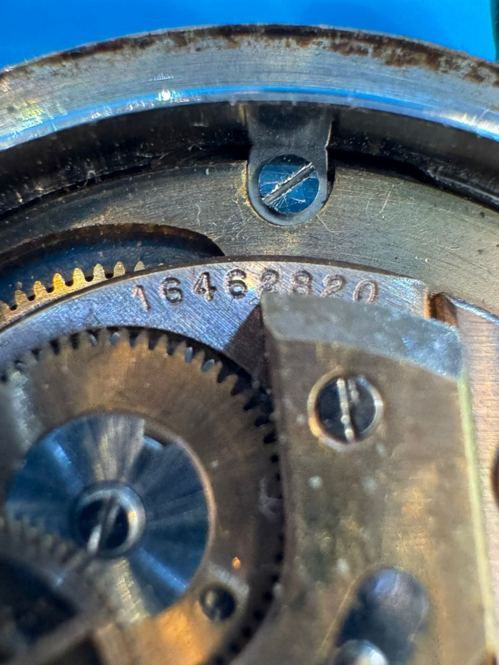A gold-plated circular vintage wristwatch featuring a cream dial, gold hour indices, and a dark blue leather strap. View VIII
