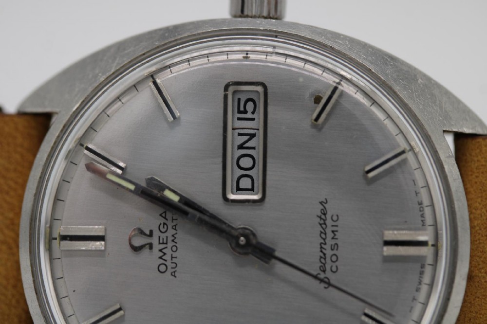 A vintage stainless steel Omega Seamaster Cosmic automatic wristwatch featuring a silver dial with day-date aperture and a tan leather strap with white stitching. View II