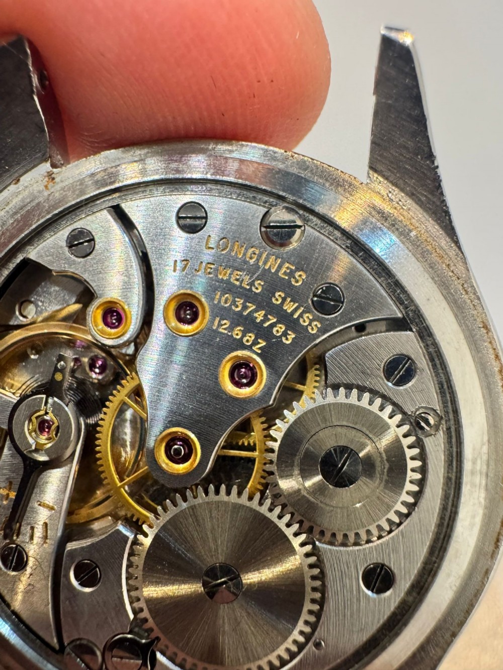 A 1950s Longines wristwatch with a stainless steel case, off-white dial with gold-tone hour markers, sub-seconds dial, and a burgundy leather strap. View III