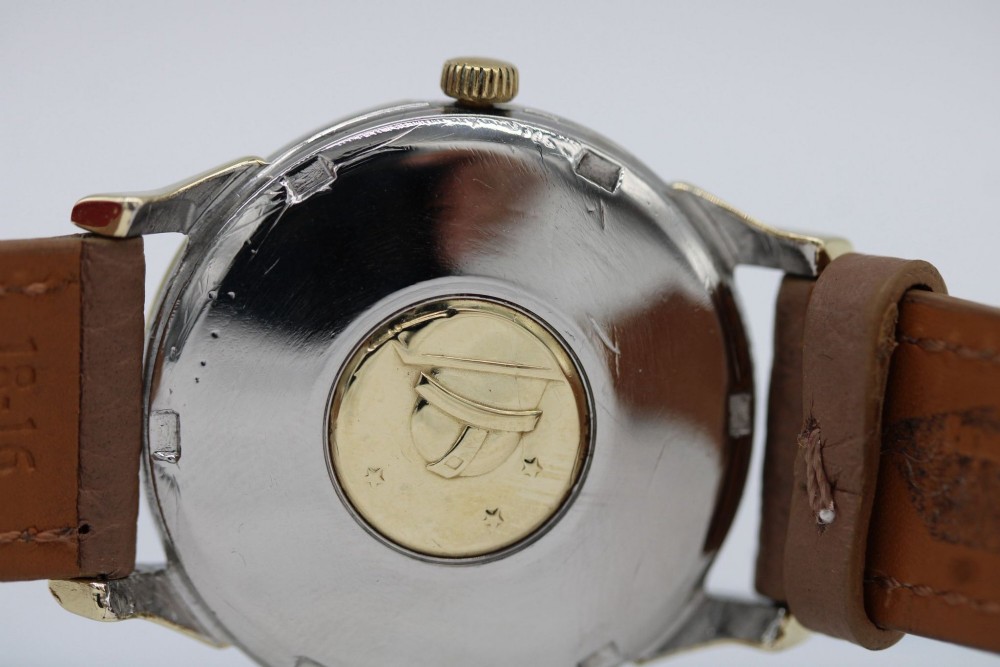 A vintage gold-plated Omega Constellation wristwatch featuring a faceted pie-pan dial, date window, and a brown leather strap. View VI