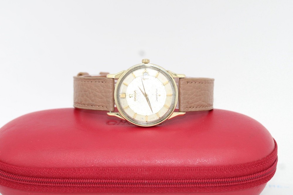 A vintage gold-plated Omega Constellation wristwatch featuring a faceted pie-pan dial, date window, and a brown leather strap. View VII