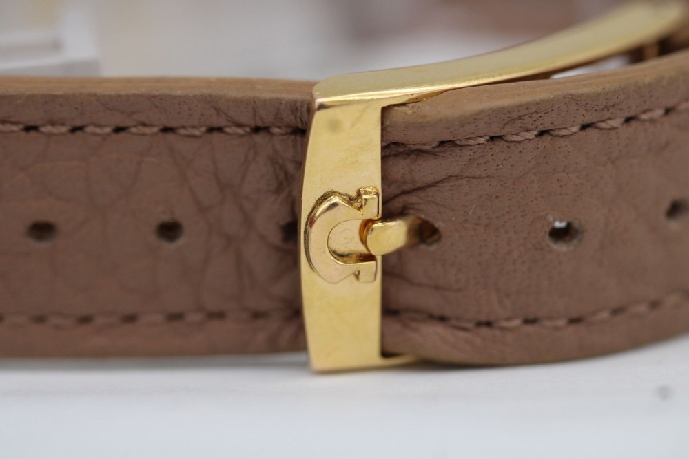 A vintage gold-plated Omega Constellation wristwatch featuring a faceted pie-pan dial, date window, and a brown leather strap. View XII