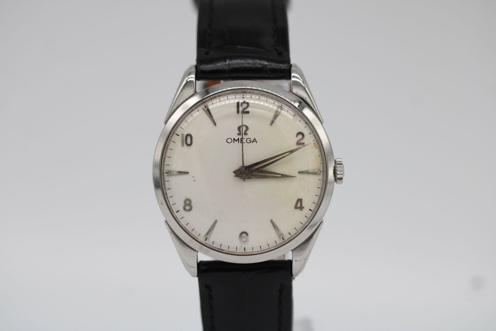 A 1960s Omega stainless steel manual-wind wristwatch featuring a silver dial with silver-toned Arabic numerals and indices on a black leather strap.