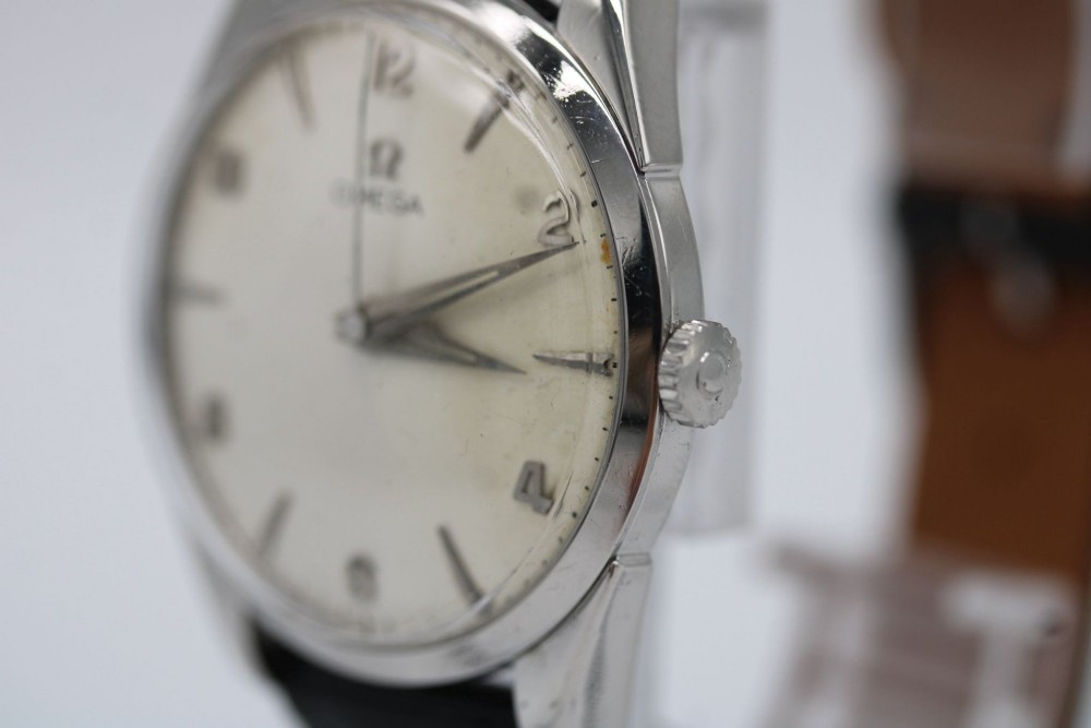 A 1960s Omega stainless steel manual-wind wristwatch featuring a silver dial with silver-toned Arabic numerals and indices on a black leather strap. View IV