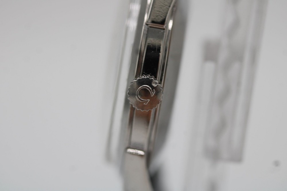 A 1960s Omega stainless steel manual-wind wristwatch featuring a silver dial with silver-toned Arabic numerals and indices on a black leather strap. View V