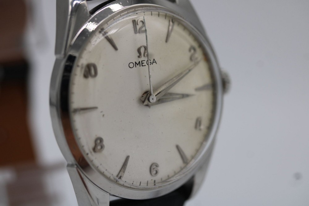 A 1960s Omega stainless steel manual-wind wristwatch featuring a silver dial with silver-toned Arabic numerals and indices on a black leather strap. View VII