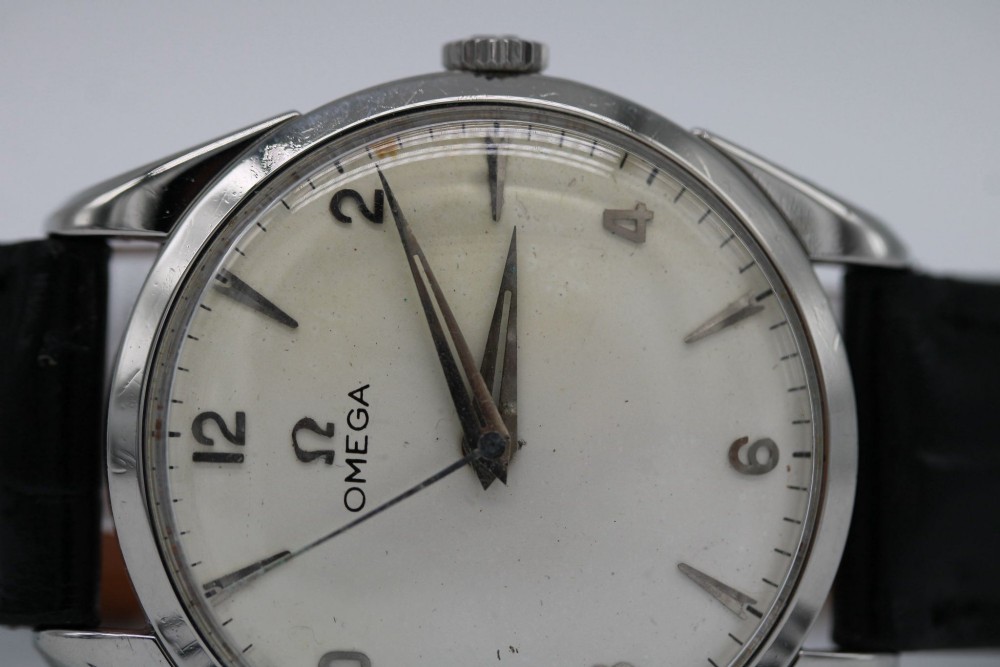 A 1960s Omega stainless steel manual-wind wristwatch featuring a silver dial with silver-toned Arabic numerals and indices on a black leather strap. View IX