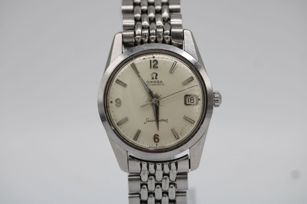 A 1960s stainless steel Omega Seamaster wristwatch with a patinated cream dial and a beads-of-rice bracelet.