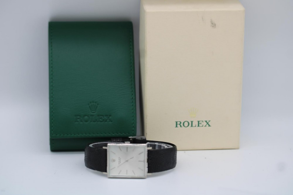 A 1960s square Rolex Cellini wristwatch featuring an 18ct white gold case, silver sunburst dial with simple index markers, and a black textured leather strap. View XIII