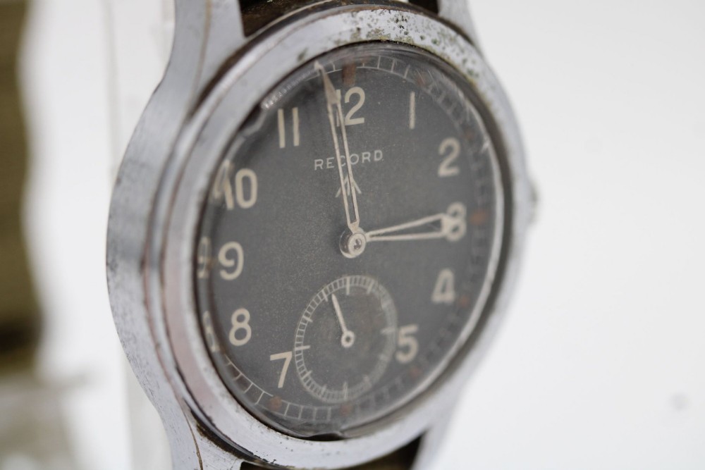 A 1940s Record military wristwatch with a black dial, Arabic numerals, broad arrow mark, and a khaki fabric strap. View II