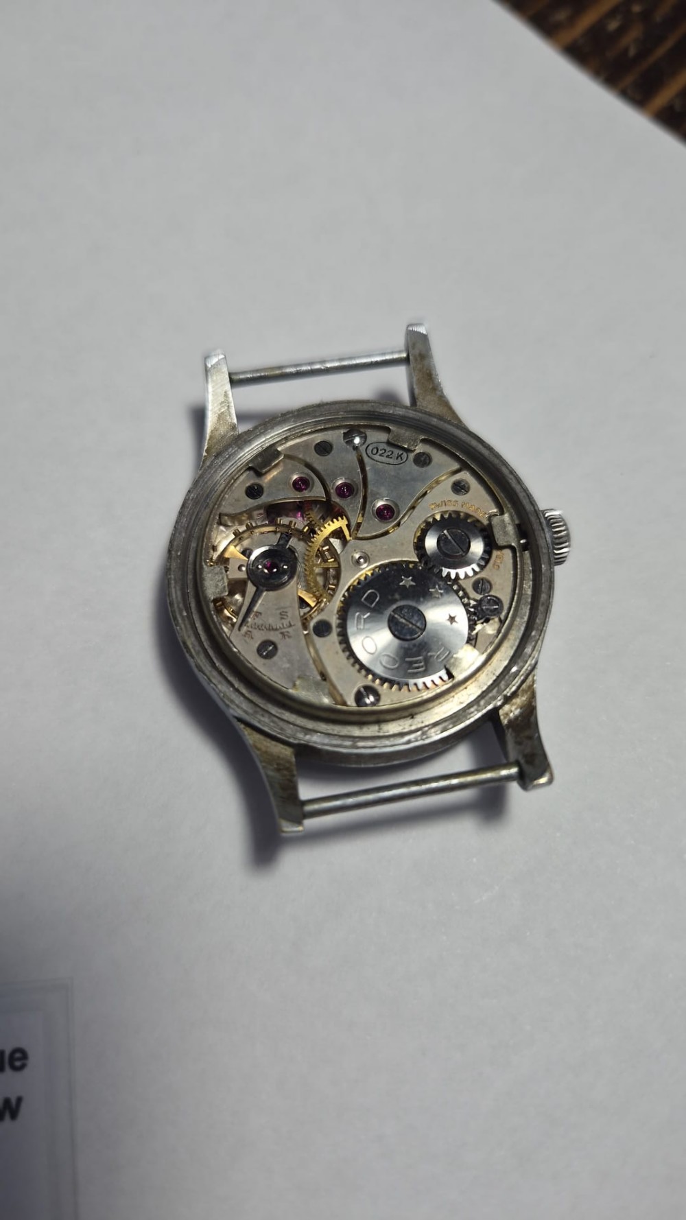 A 1940s Record military wristwatch with a black dial, Arabic numerals, broad arrow mark, and a khaki fabric strap. View IV