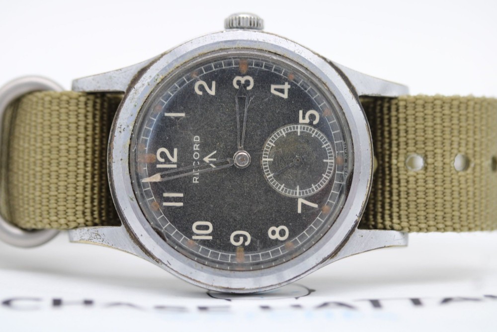 A 1940s Record military wristwatch with a black dial, Arabic numerals, broad arrow mark, and a khaki fabric strap. View VIII