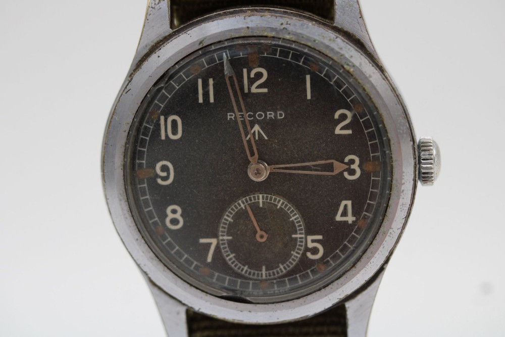 A 1940s Record military wristwatch with a black dial, Arabic numerals, broad arrow mark, and a khaki fabric strap. View IX