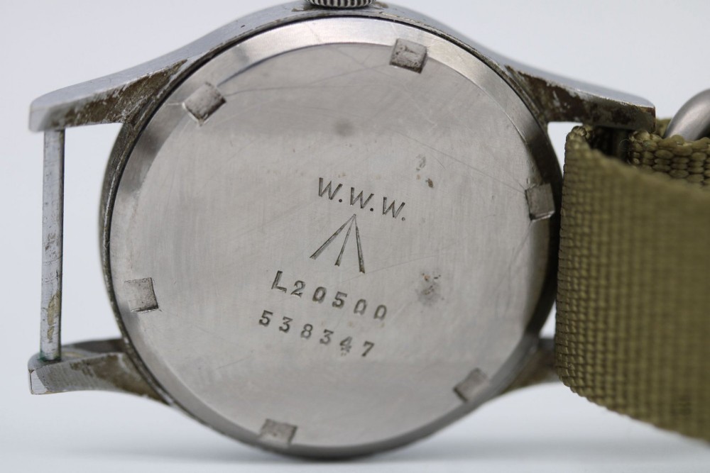 A 1940s Record military wristwatch with a black dial, Arabic numerals, broad arrow mark, and a khaki fabric strap. View XI
